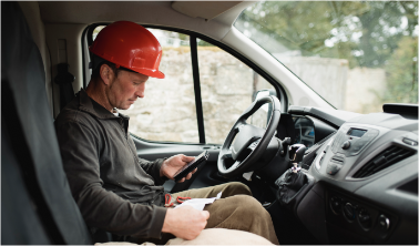 Lioton 1000 at work,  A man wearing a red hardhat, sitting in a work truck, checking his phone.